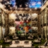 styleized image of a mirrored courtyard with low patio furniture. Buildings are visible in the distance.
