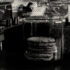 Stylized halftone pictures of cookies and granola in jars, a menu and a tip jar on a dark surface while coffee prep station is visible in the background